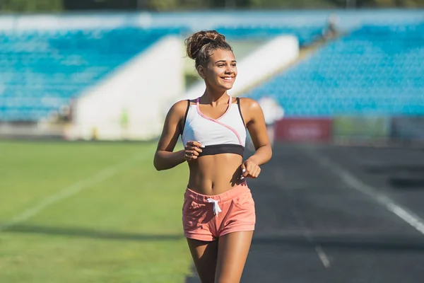 A rapariga está a correr pelo estádio. Treinamento ao ar livre — Fotografia de Stock