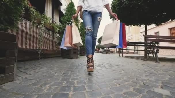 Miután a bevásárló nap. Közeli kép a fiatal nő, könyv bevásárló táskák, míg az utcán. Lassú mozgás — Stock videók