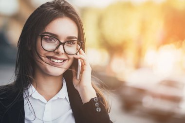 Mutlu genç kadın sokakta yürürken cep telefonda konuşurken gözlük. yakın çekim. Güneş arka plan