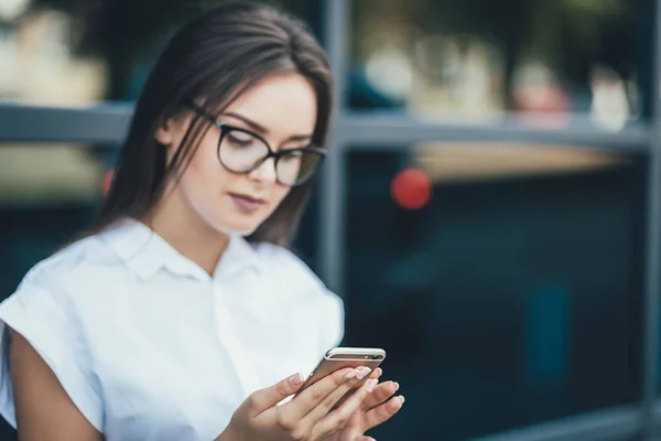 Beautiful young businesswoman wearing white shirt and using modern smart phone while walking at break in the city, professional female employer typing text message on cellphone outside — Stock Photo, Image