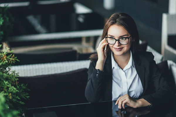 An attractive modern business woman speaks on the phone with a client. Rest in a cafe. Business lunch — Stock Photo, Image