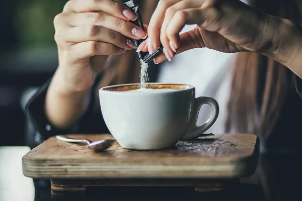 A mão das meninas derrama açúcar em seu café. Fechar — Fotografia de Stock