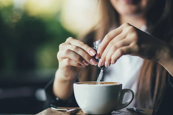 Žena přidávání cukru do čerstvé aromatické kávy na stole, closeup — Stock fotografie