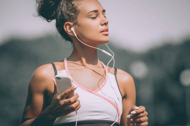 Spor spor Stadı'nda müzik dinlemek cep telefonu kullanan kadın. Yakın çekim. Gri arka plan