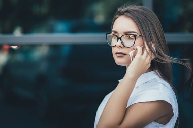 Şehirde bir sokakta Smartphone kullanarak iş kadını. Genç profesyonel iş kadını akıllı telefonda konuşurken. Şehir yaşam tarzı