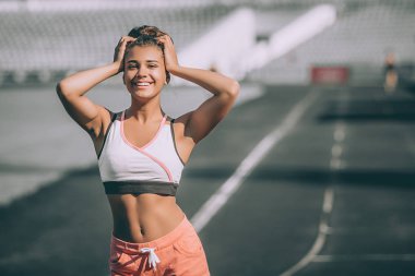 Seksi spor kız Stadı'nda poz. Fitness Spor şekil şort ve tank top stadyumda kızla. Kız spor gün sonra