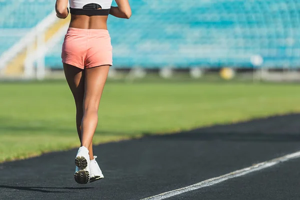 Vista trasera de una deportista en forma corriendo una distancia en el estadio — Foto de Stock
