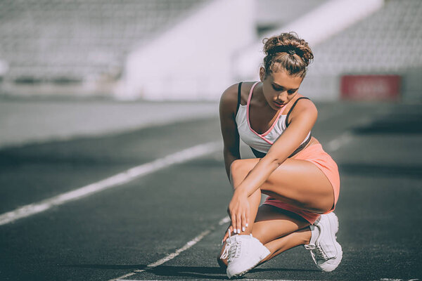 Close up portrait of sporty woman having ankle injury in running track., Healthcare and sport concept. Grey backround