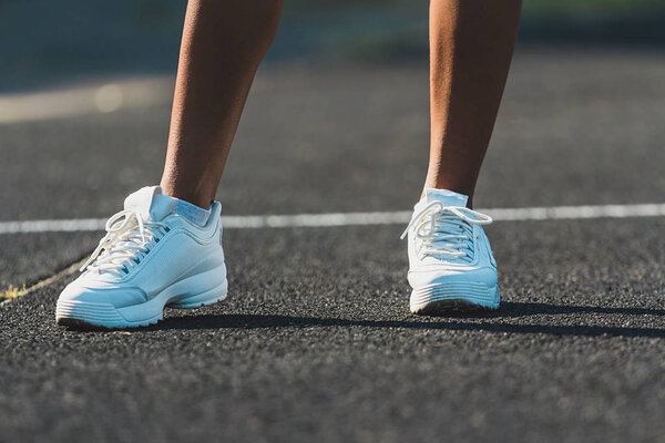 Womans legs in white running shoes standing on asphalt