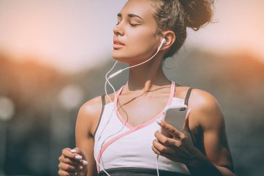 Ciddi kadın jogger emin arıyorum. Genç fitness kadın müzik dinleme eğitim açık havada, stadyum parkur sonra kulaklıklarla. Kız kulaklık smartphone üzerinden müzik dinle