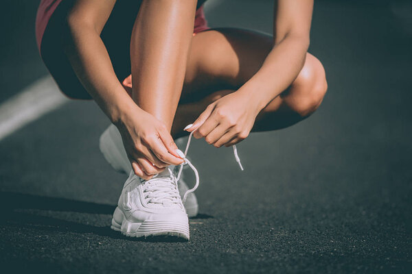 Womans hand tying shoe laces at stadium. Preparation for running. Close up. Front view