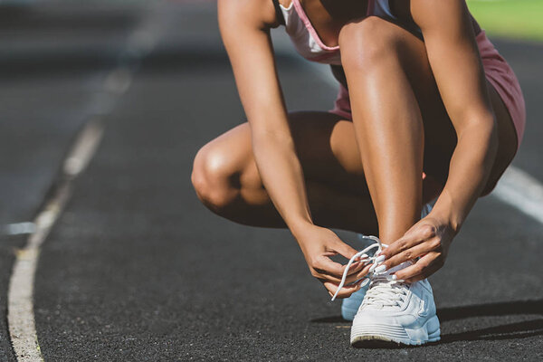 A young woman stopped to tie a string while running in the stadium