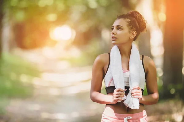 Portrait young attractive fit woman with white towel resting after workout sport exercises outdoors on a background of park trees. Healthy lifestyle well being wellness happiness concept. Sunshine — Stock Photo, Image