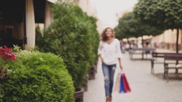 Felice donna fashion-monger con borse della spesa a piedi lungo la strada — Video Stock