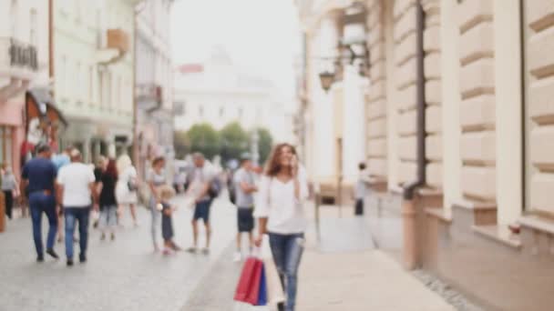 Молодая женщина на улице с сумками разговаривает по мобильному телефону — стоковое видео