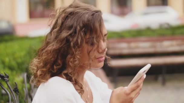 Mulher usando Smartphone Relaxa no banco. Tecnologia ao ar livre. Fechar — Vídeo de Stock