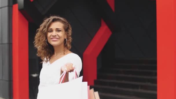 Piękna kobieta, trzymając torby na zakupy i uśmiechając się - na zewnątrz — Wideo stockowe