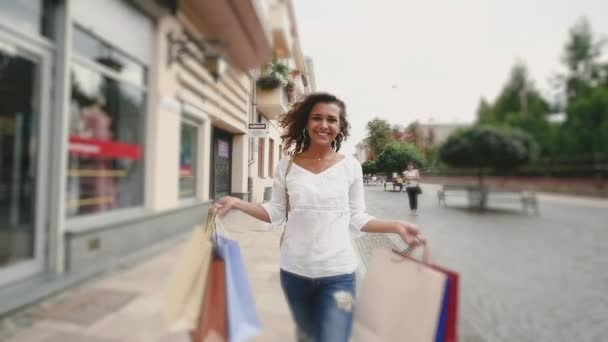 Bella giovane donna che cammina felicemente dopo lo shopping. rallentatore — Video Stock