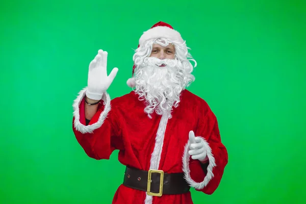 Санта-Клаус смотрит на камеру и машет зеленым экраном — стоковое фото