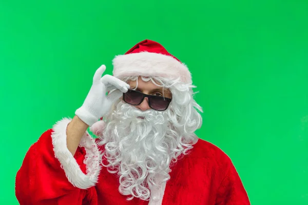 Santa claus posing with sunglasses against green background — Stock Photo, Image