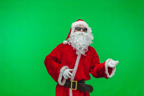 Santa in zonnebril imaginaire gitaarspelen op Kerstfeest op groene achtergrond Chromakey — Stockfoto