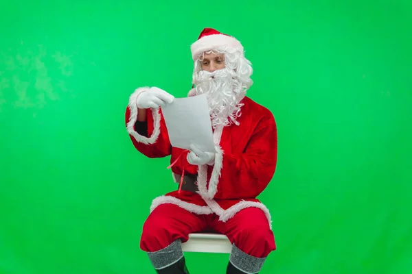 Weihnachtsmann liest auf grünem Bildschirm Briefe von Kindern vor — Stockfoto