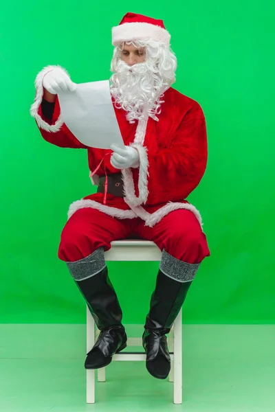 Weihnachtsmann sitzt auf Stuhl mit Buchstaben in den Händen auf einem grünen Bildschirm Chromschlüssel — Stockfoto