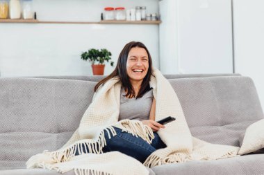 Kadın Tv kanepede görünüyor.