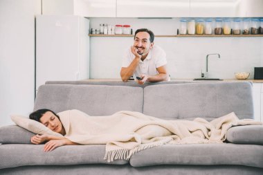 Bir adam Tv ararken bir kadın yatıyor