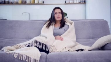 Bir kadın bir battaniye ile Tv izliyor