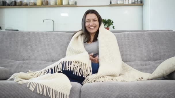 Una mujer está viendo la televisión con una manta — Vídeos de Stock