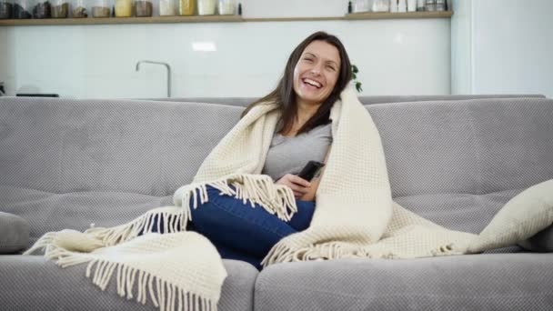 Une femme regarde la télé avec une couverture — Video