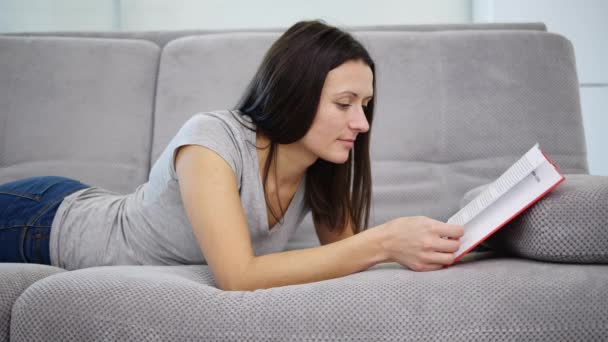 Una mujer leyendo un libro rojo — Vídeos de Stock