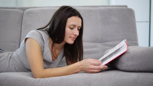 Una mujer leyendo un libro rojo — Vídeos de Stock