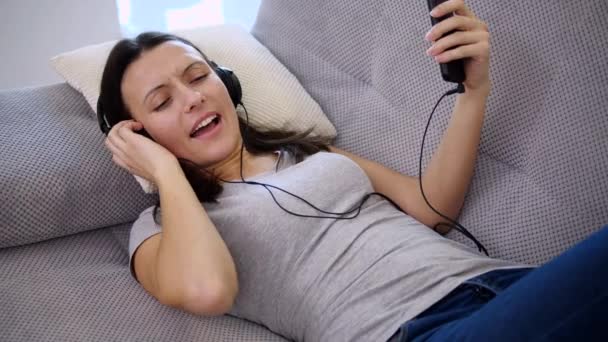 Uma mulher ouve música em fones de ouvido — Vídeo de Stock
