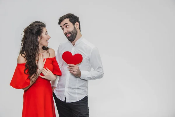 Família, férias, Dia dos Namorados. O conceito de pessoas de amor - um grande plano. Segura o coração de papel vermelho. Fundo branco. Vestido com uma camisa branca e um vestido vermelho . — Fotografia de Stock