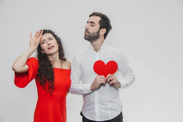 Família, férias, Dia dos Namorados. O conceito de pessoas de amor - um grande plano. Segura o coração de papel vermelho. Fundo branco. Vestido com uma camisa branca e um vestido vermelho . — Fotografia de Stock