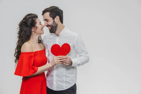 Familj, helgdagar, alla hjärtans dag. Älskar människor Concept-en stor plan. Håll det röda papperets hjärta. Vit bakgrund. Klädd i en vit skjorta och en röd klänning. — Stockfoto