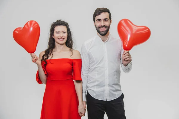 Casal romântico bonito isolado no fundo branco. Uma jovem atraente e belas mãos levantam balões na forma do coração. Dia dos Namorados — Fotografia de Stock