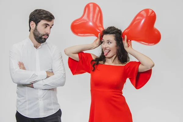 Beau couple romantique isolé sur fond blanc. Une jolie jeune femme tient les ballons au-dessus de sa tête, son mari la regarde alors avec étonnement. Saint Valentin — Photo