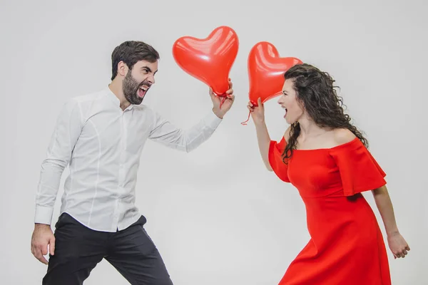 Casal romântico bonito isolado no fundo branco. Uma jovem atraente e belas mãos levantam balões na forma do coração. Sorrindo. . — Fotografia de Stock