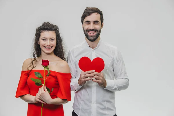 Belo casal jovem. Gostar de passar o tempo em conjunto em celebração do Dia de São Valentim. Durante este tempo, mantém corações de papel e uma rosa vermelha. Feliz e apaixonado . — Fotografia de Stock