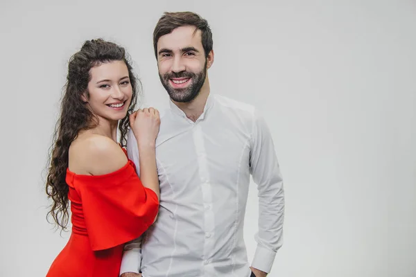 Man and woman with long hair. The wife put her hands on the shoulder of her husband with love. Valentines Day. A woman dressed in a red dress, a man in a white shirt. — ストック写真