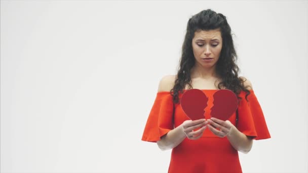 Portrait of beautiful woman on white background. Bad Valentines Day. Concept, model holds red heart in hand. — Stockvideo