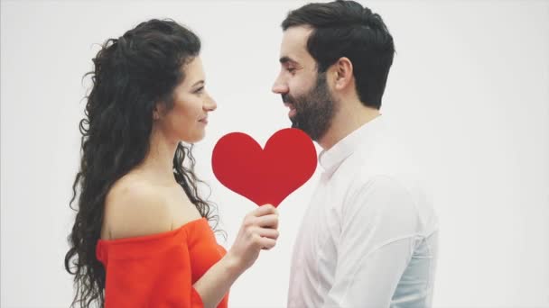 Bella coppia romantica isolata su sfondo bianco. Attraente giovane donna e bello abbraccio mano con cuore rosso. Buon San Valentino bacio . — Video Stock