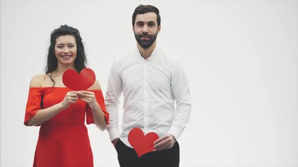 Güzel romantik çift beyaz arka plan üzerinde izole. Çekici bir genç kadın ve yakışıklı bir adam ellerinde kırmızı kalpler tutun. Sevgililer Günü — Stok video