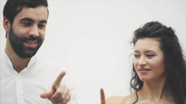 Güzel genç bir çift. İnanılmaz hava aşık, parmakları bir kalp öpüşme çizin. Sevgililer günü kutlama. Kırmızı elbiseli bir beyaz gömlek kız adam giymiş.