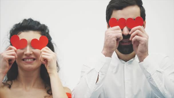 Hermosa pareja romántica aislada sobre fondo blanco. Una joven atractiva vestida con un vestido rojo, un hombre guapo con una camisa blanca . — Vídeos de Stock