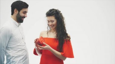 Güzel genç bir çift. Sevgililer günü kutlama. Bir adam bir hediye kutusu verir. Bir kız bir kutu hediye görmüyor açığa kırmızı bir elbise giymiş.