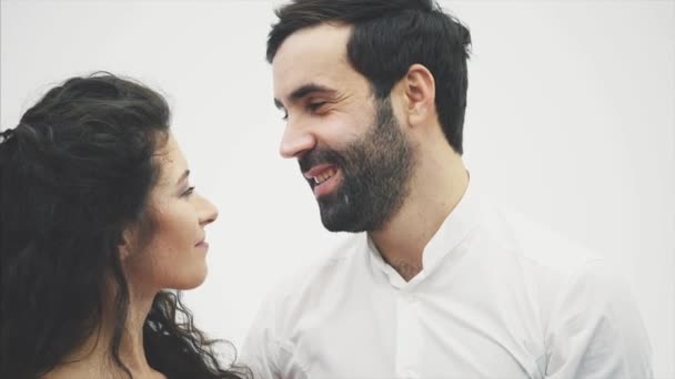 Belo casal jovem. Abraçando beijos e curtindo o tempo juntos. Celebração do Dia dos Namorados. Juntos, levante a caixa de presente. A menina está vestida com um vestido vermelho e seu marido em uma camisa branca — Vídeo de Stock